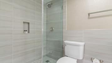 A modern bathroom with a glass-enclosed shower, a toilet, and a towel rack.