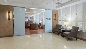 A lobby with a tiled floor, seating area with chairs and a table, and a sign reading "Patio Grille & Lounge". - Crowne Plaza Executive Center Baton Rouge by IHG (Baton Rouge)