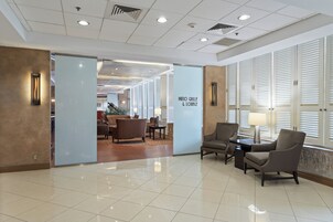 Un vestíbulo con piso de baldosas, zona de estar con sillas y una mesa, y un letrero que dice "Patio Grille & Lounge".