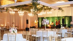 A banquet hall with round tables covered in white tablecloths, gold chairs, and floral centerpieces. - Crowne Plaza Executive Center Baton Rouge by IHG (Baton Rouge)