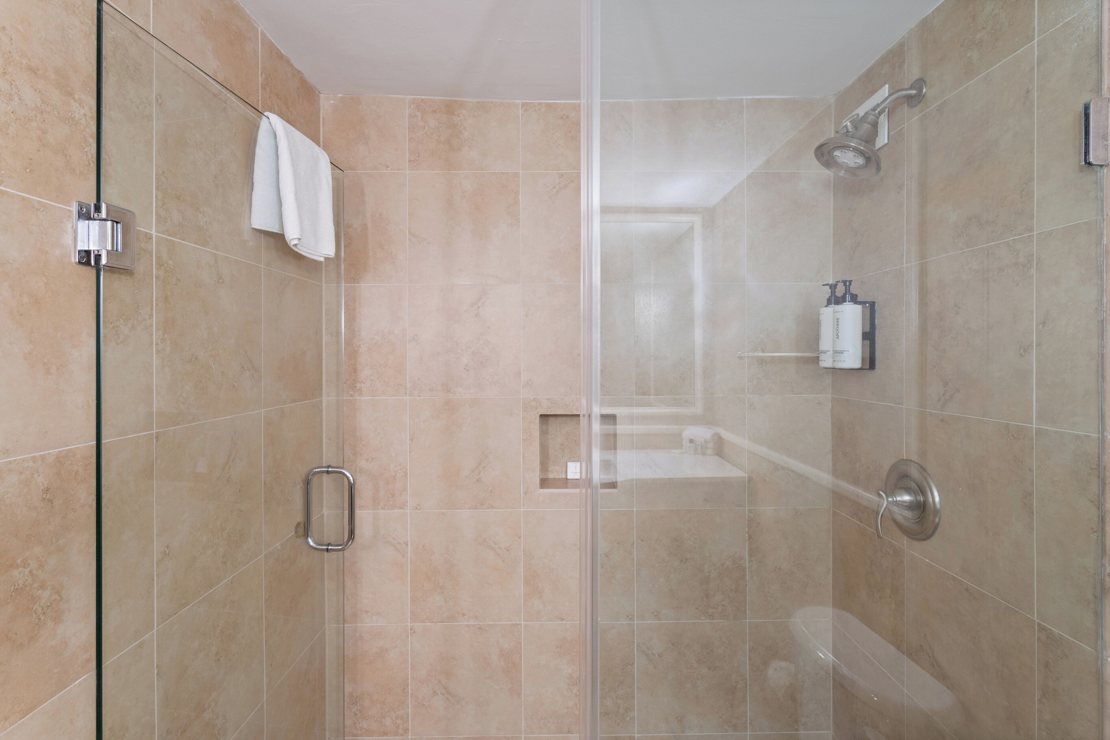 Une salle de bain moderne avec une douche à parois de verre, un porte-serviettes apparent et une petite étagère contenant des articles de toilette.