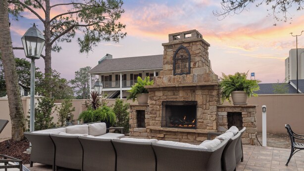 An outdoor seating area with a stone fireplace, a large wicker sofa, and a potted plant. - Crowne Plaza Executive Center Baton Rouge by IHG (Baton Rouge)