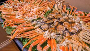 A buffet table with various seafood items, including crab legs and oysters, arranged on a bed of lettuce.