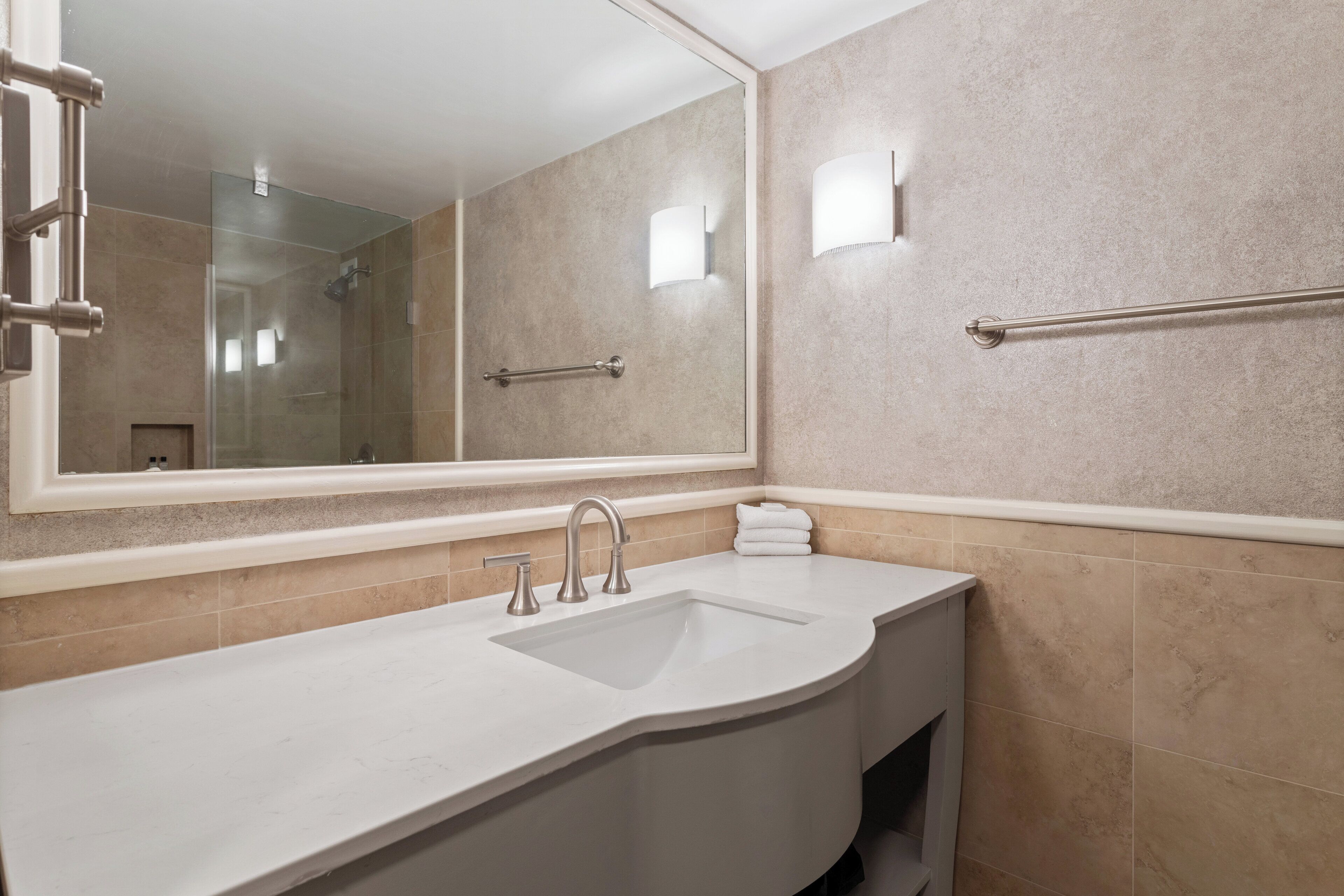 A modern bathroom with a large sink, a mirror, and a glass shower enclosure.
