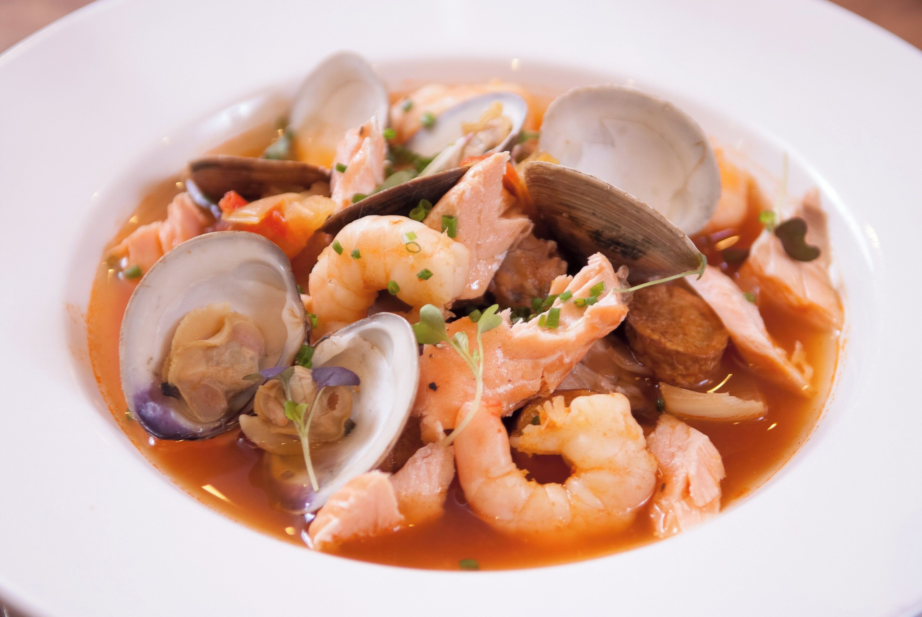 A seafood dish with clams, shrimp, and mussels in a broth.