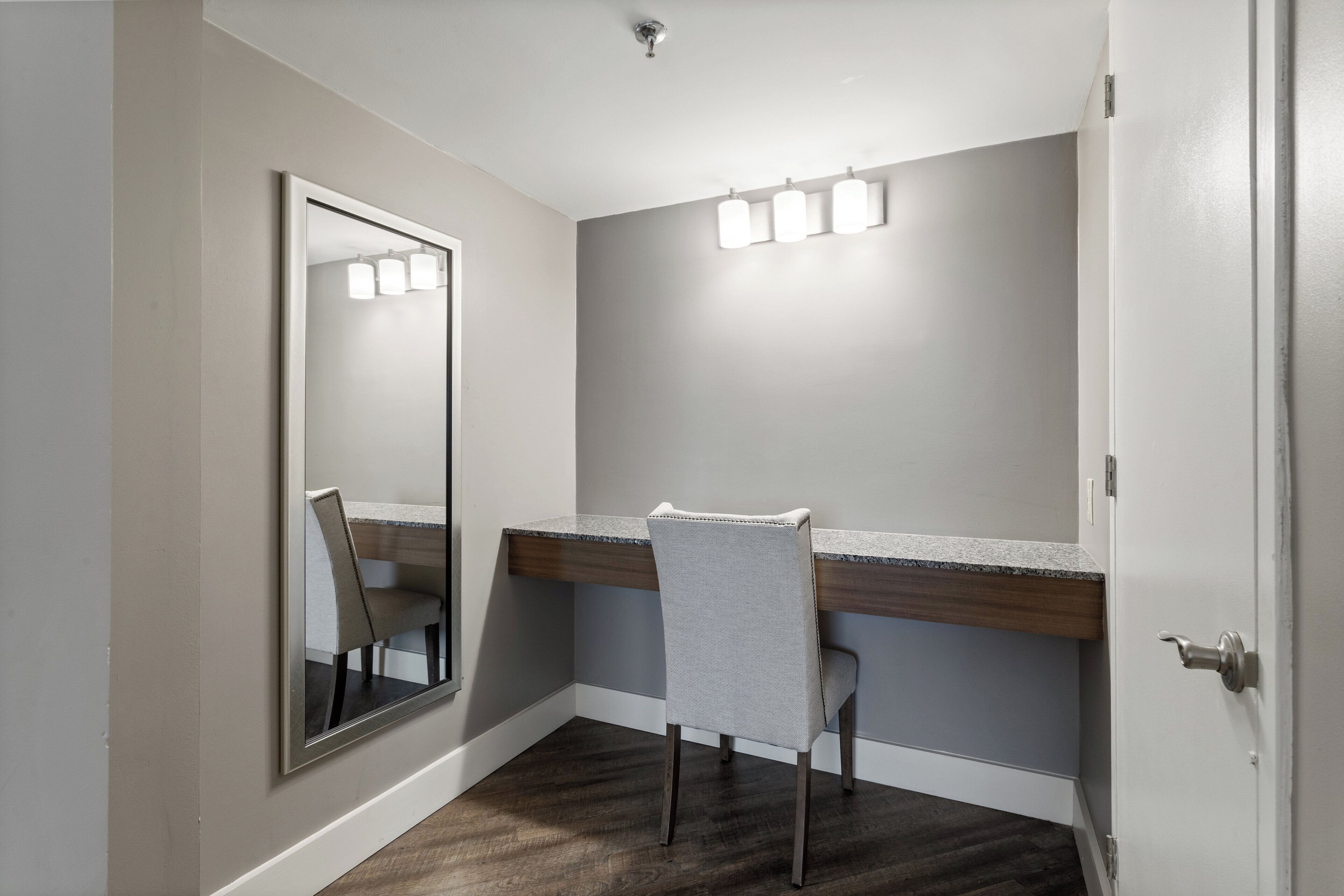 A bathroom with a mirror, vanity, and a chair.
