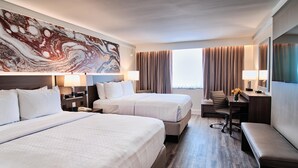 A hotel room with two beds, a desk, a chair, and a large abstract painting on the wall. - Crowne Plaza Executive Center Baton Rouge by IHG (Baton Rouge)