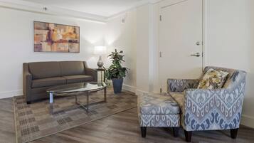 A living room with a sofa, armchair, coffee table, lamp, and a painting on the wall.