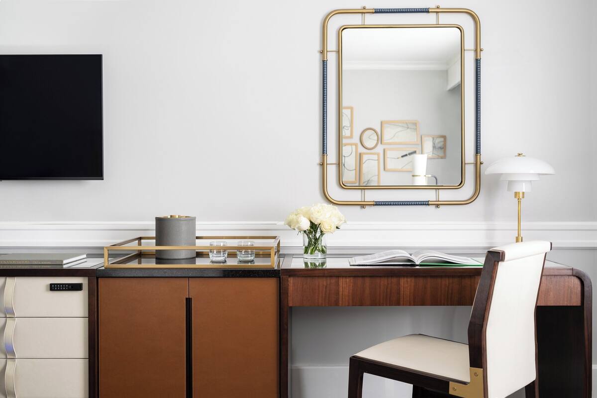 Un bureau moderne agrémenté d’un miroir, d’une lampe et d’un vase de fleurs.