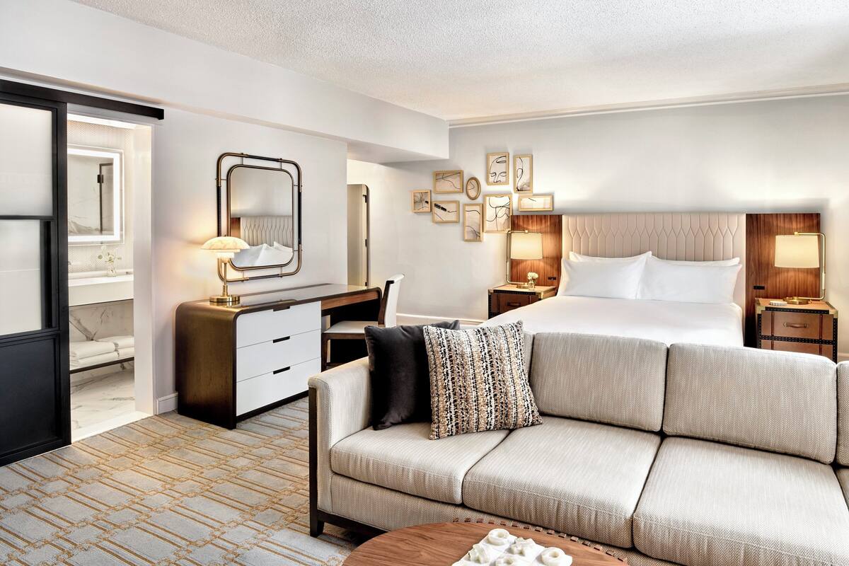 Une chambre d’hôtel comprenant un lit, un canapé, un bureau, une commode et un miroir.