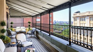 A covered balcony with outdoor seating, a view of a cityscape, and a building with a dome in the background. - Omni Parker House  (Boston)