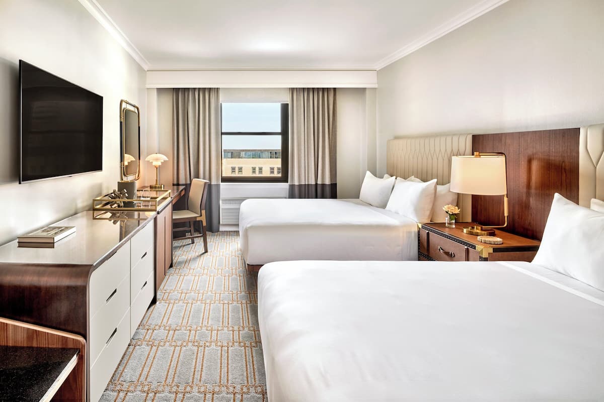 Une chambre d’hôtel avec un lit, un bureau, une télévision et une fenêtre avec des rideaux.