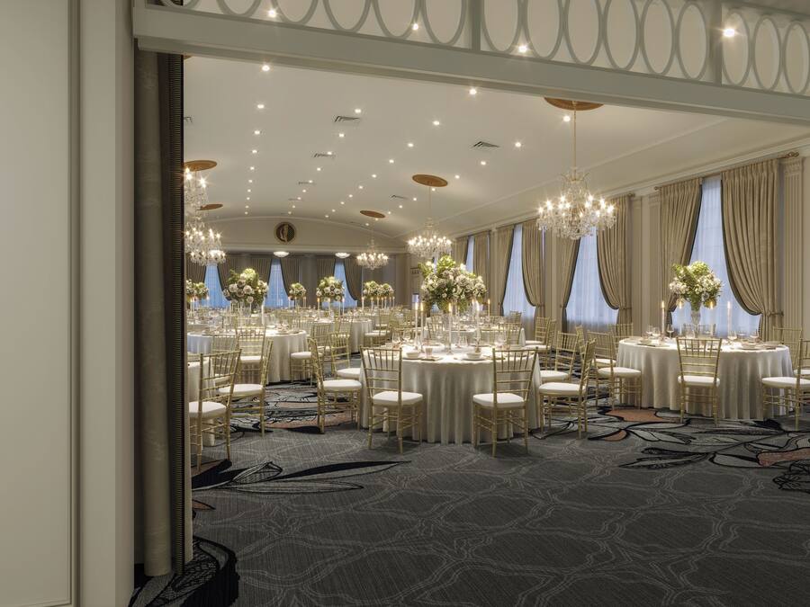 Un amplio salón de banquetes elegantemente decorado con mesas redondas, sillas doradas y candelabros.