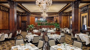 A formal dining room with multiple tables, elegant chandeliers, and ornate wood paneling. - Omni Parker House  (Boston)