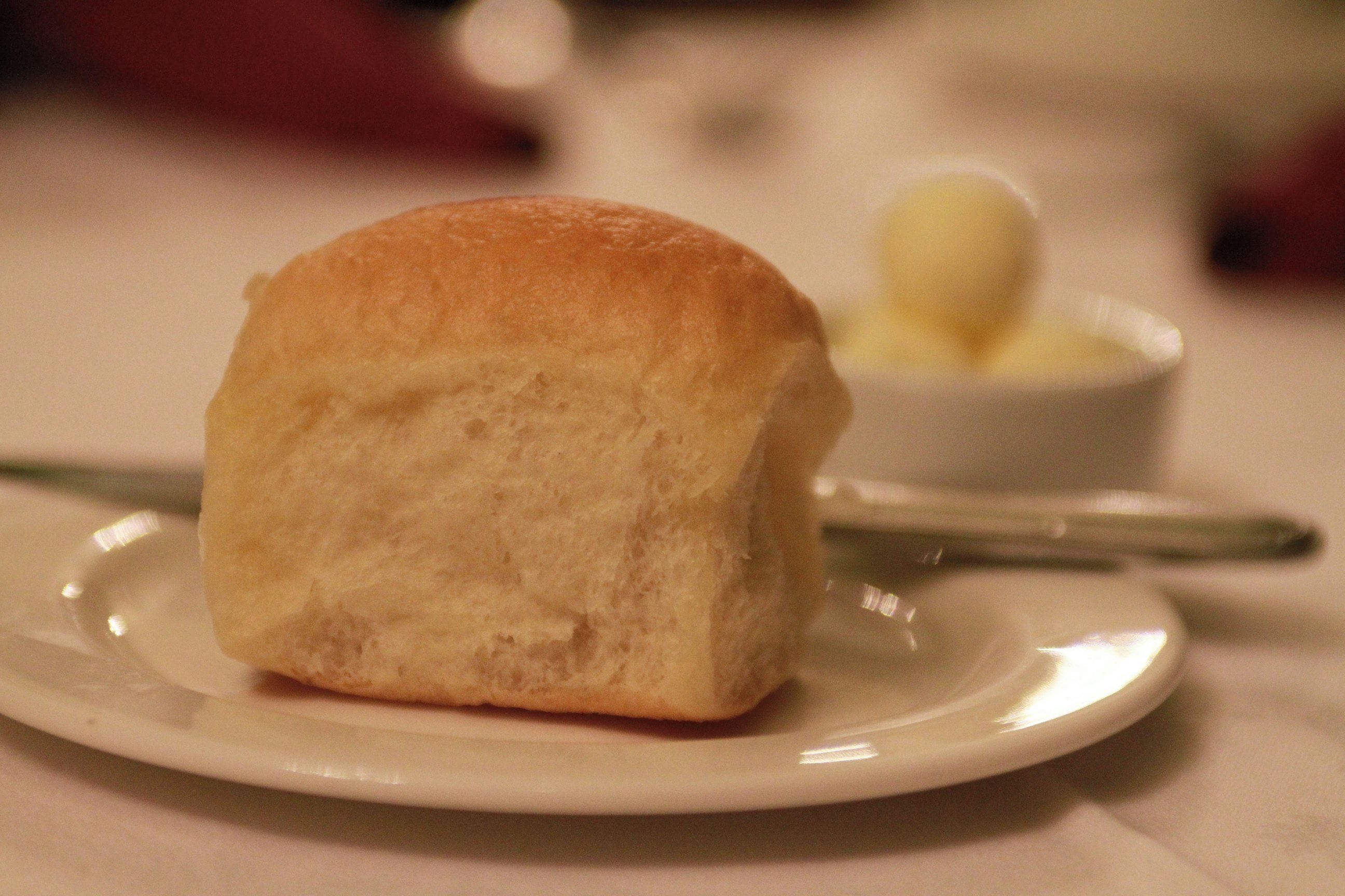 A single piece of bread on a plate with a knife beside it.