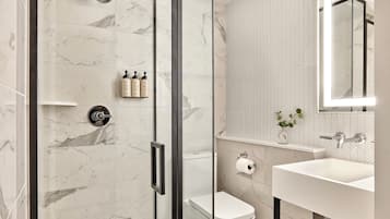 Une salle de bain moderne avec une douche à parois de verre, des toilettes et un lavabo avec un miroir.