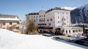 Un hotel con un edificio grande, un paisaje nevado y montañas al fondo.