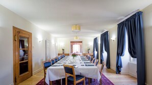 Una larga mesa de comedor con sillas, un tapete rojo con estampado y una puerta de madera a la izquierda.