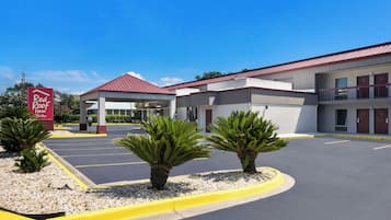 A Red Roof Inn Suites with a parking lot, a covered entrance, and a building with a red roof.