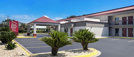 A Red Roof Inn Suites with a parking lot, a covered entrance, and a building with a red roof.
