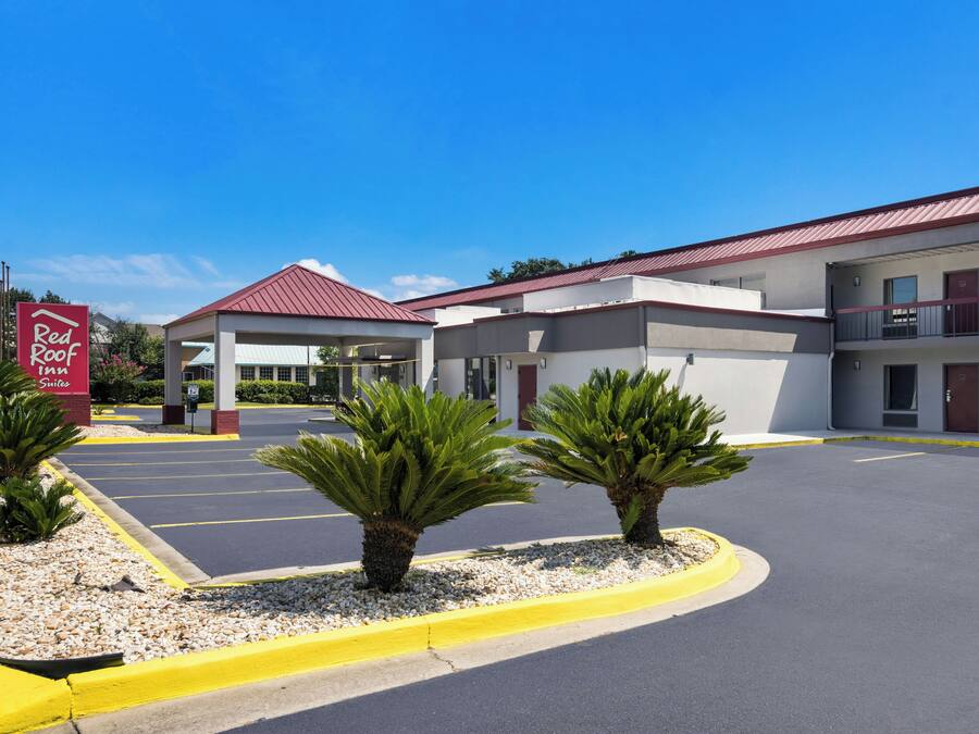 A Red Roof Inn Suites with a parking lot, a covered entrance, and a building with a red roof.
