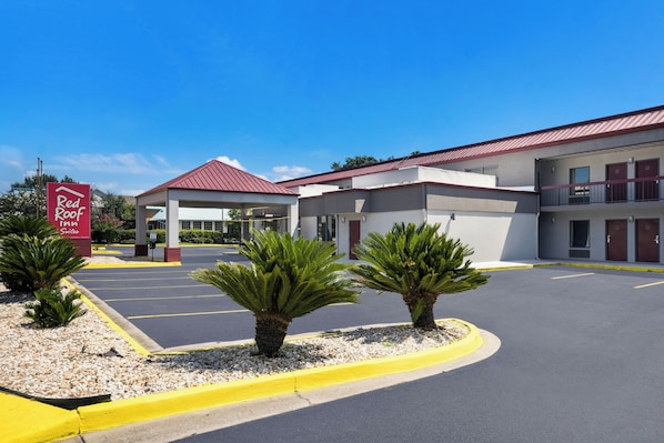 A Red Roof Inn Suites with a parking lot, a covered entrance, and a building with a red roof.