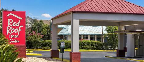 A Red Roof Inn Suites with a covered parking area and a clear sky.