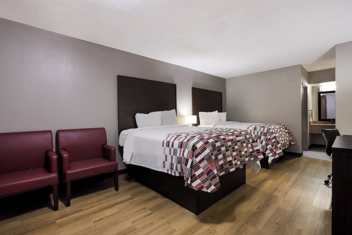 Een hotelkamer met een groot bed, een rode bank en een houten vloer.