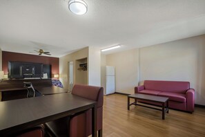 A modern living room with a wooden floor, a red sofa, a small table, and a TV in the background.