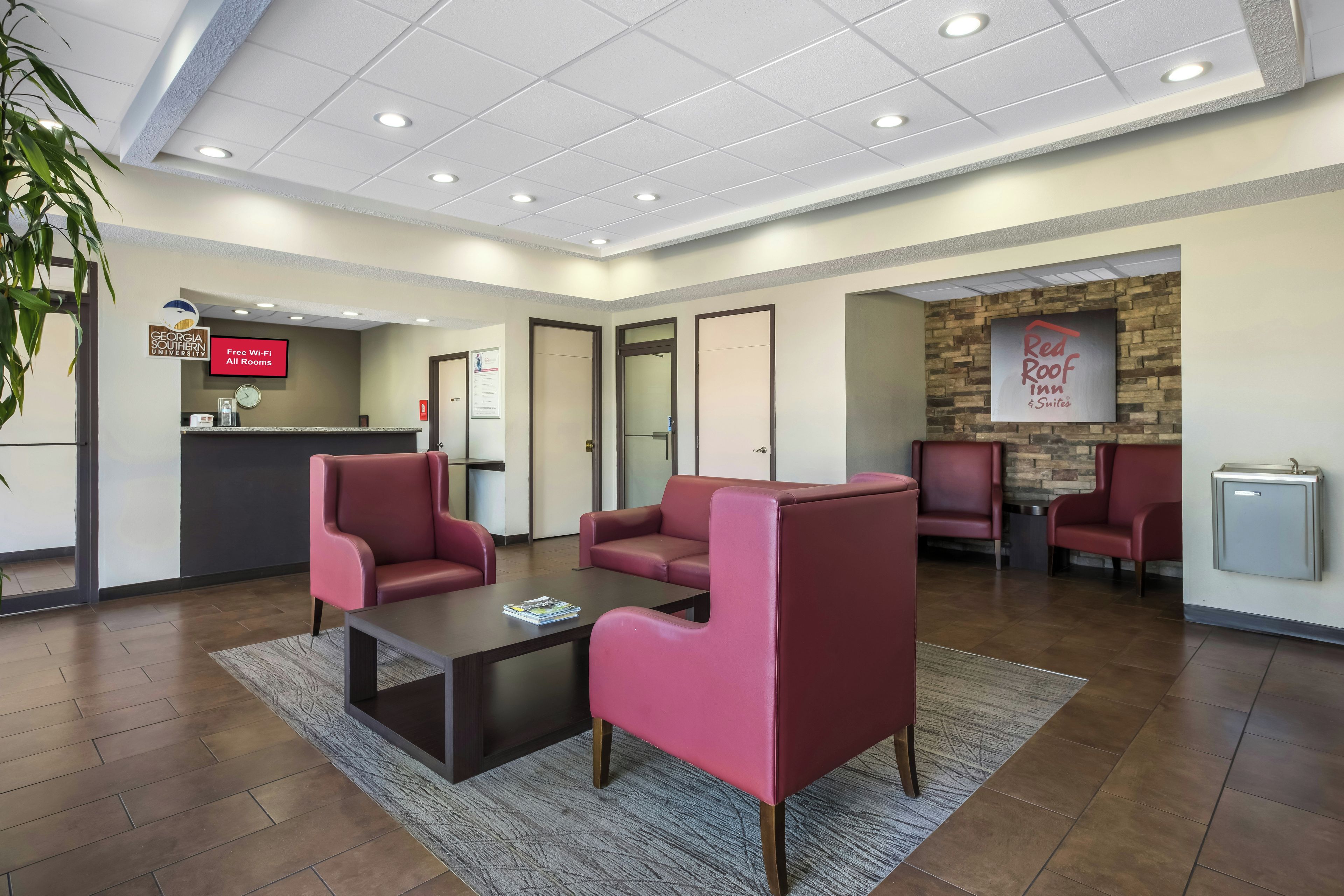 Un hall d'entrée avec des sièges rouges, un comptoir d'accueil et une enseigne Red Roof Inn.