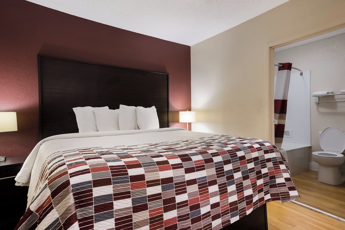 Hotelkamer met een groot bed, nachtkastje, bedlampje, een badkamer met toilet en douche.