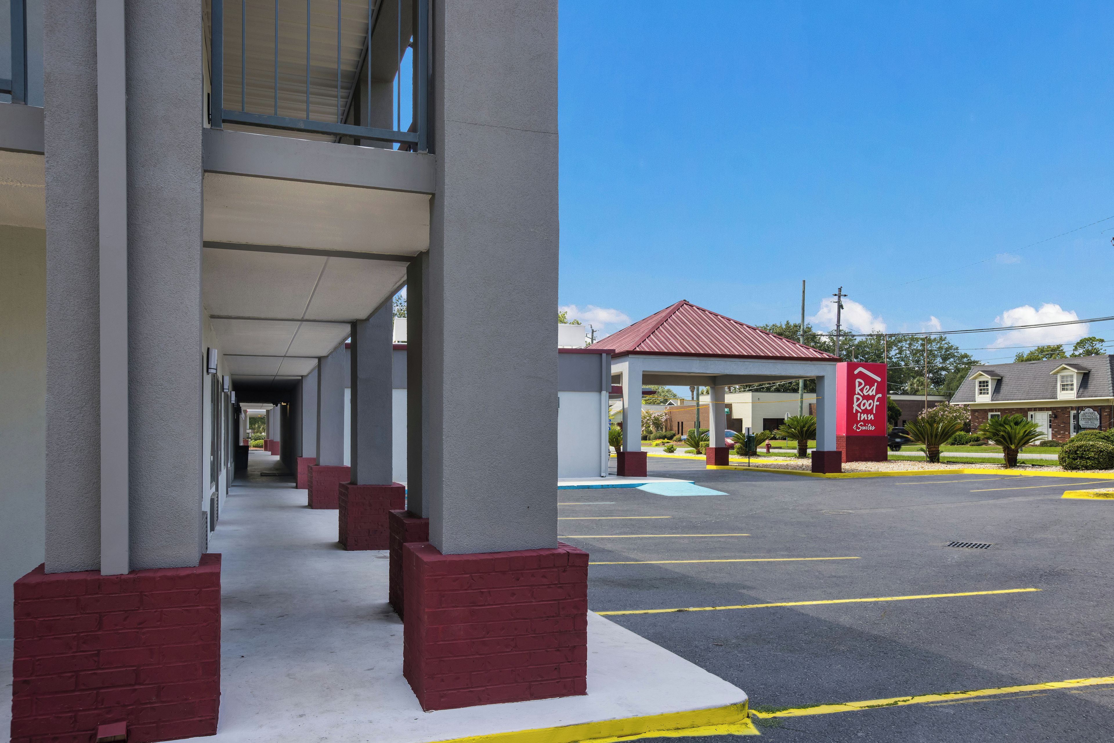 A hotel with a covered walkway and a parking lot.