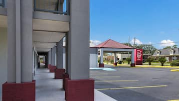 A hotel with a covered walkway and a parking lot.