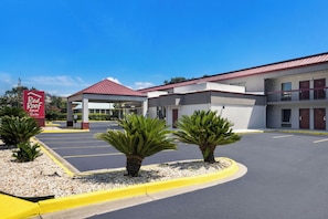 Een Red Roof Inn Suites met een parkeerplaats, een overdekte ingang en een gebouw met een rood dak.