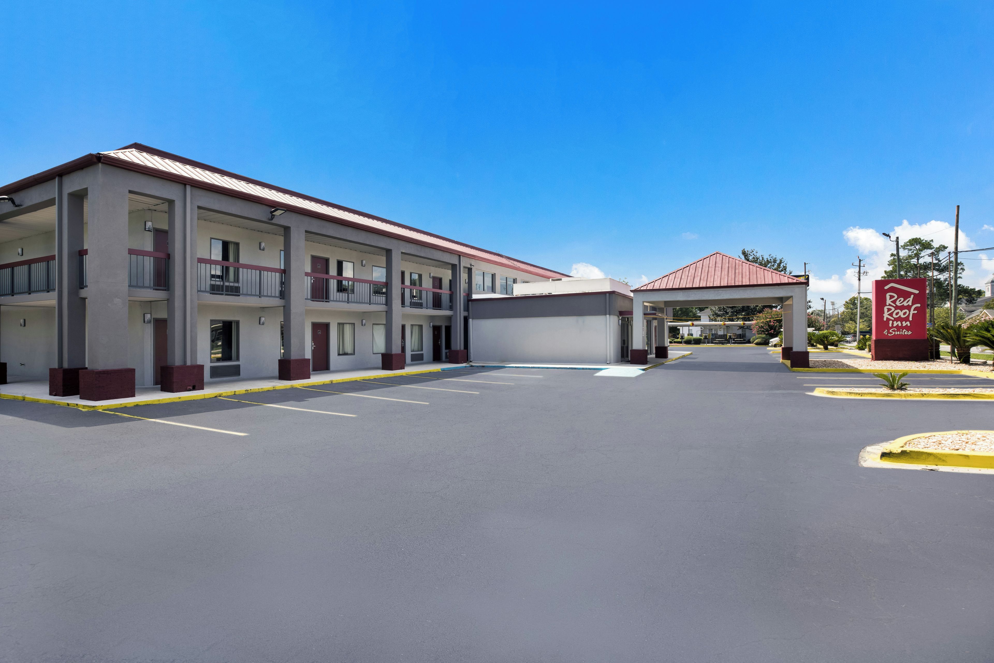 A multi-story motel with a red roof and a covered entrance.
