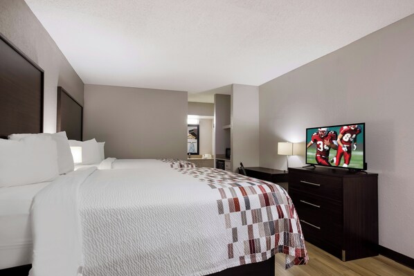 Una habitación de hotel con una cama grande, televisión, escritorio y armario.