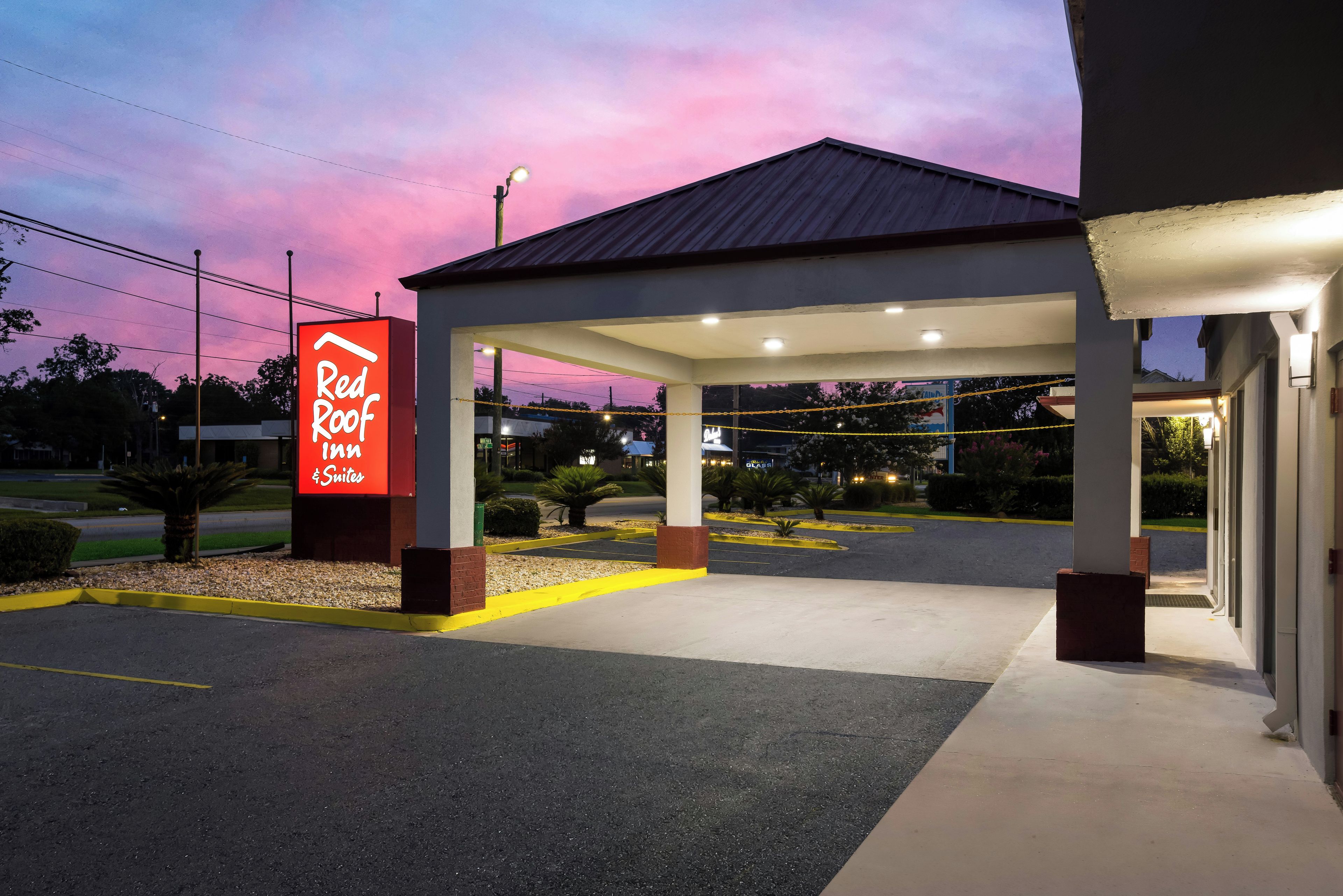 Un Red Roof Inn & Suites con area parcheggio coperta e cielo sereno.