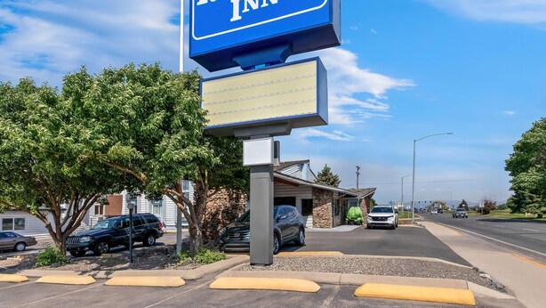 A sign for Rodeway Inn with a clear view of the parking lot and a building in the background.