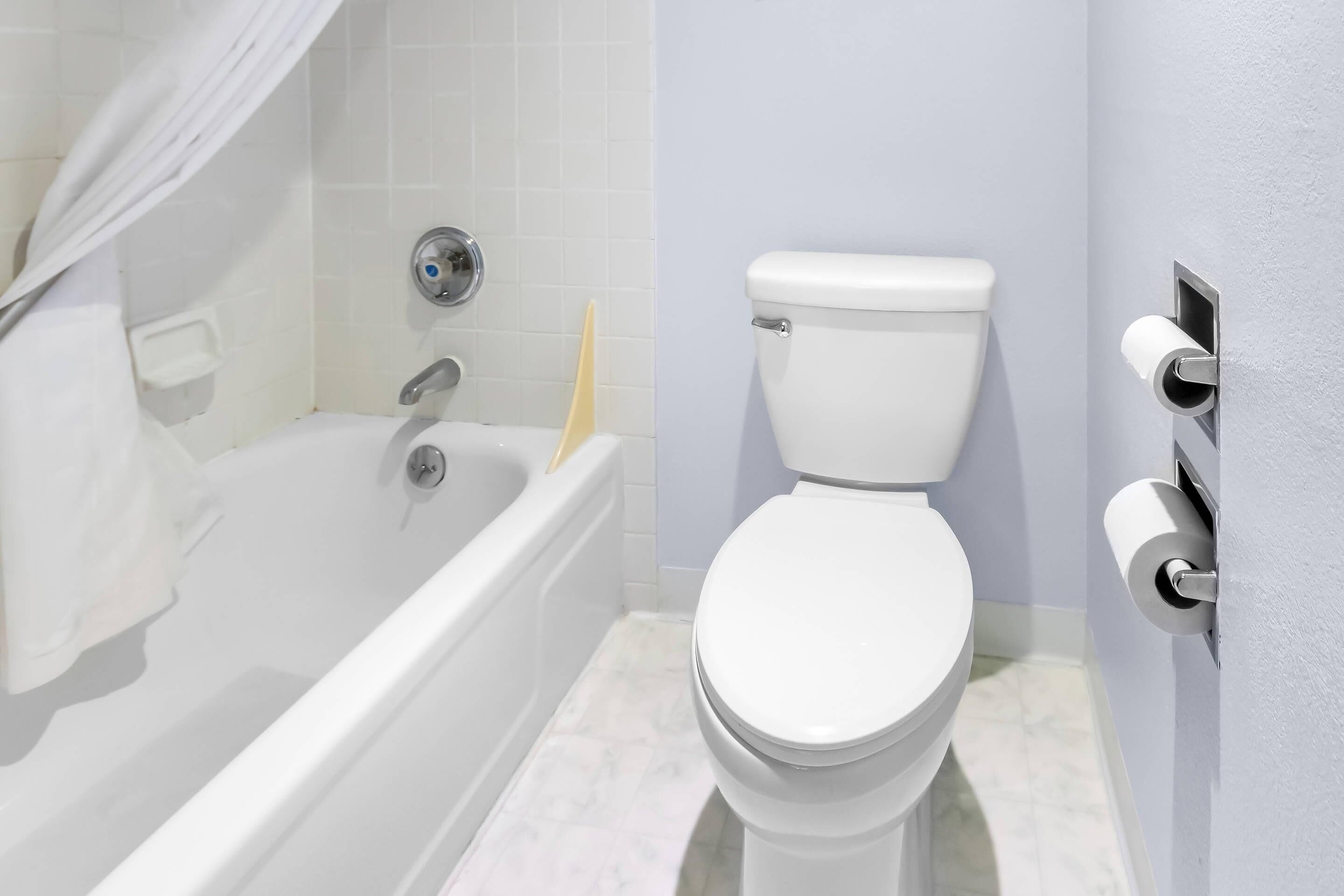A bathroom with a white bathtub, a toilet, and a towel rack.