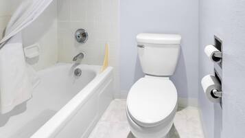 A bathroom with a white bathtub, a toilet, and a towel rack.