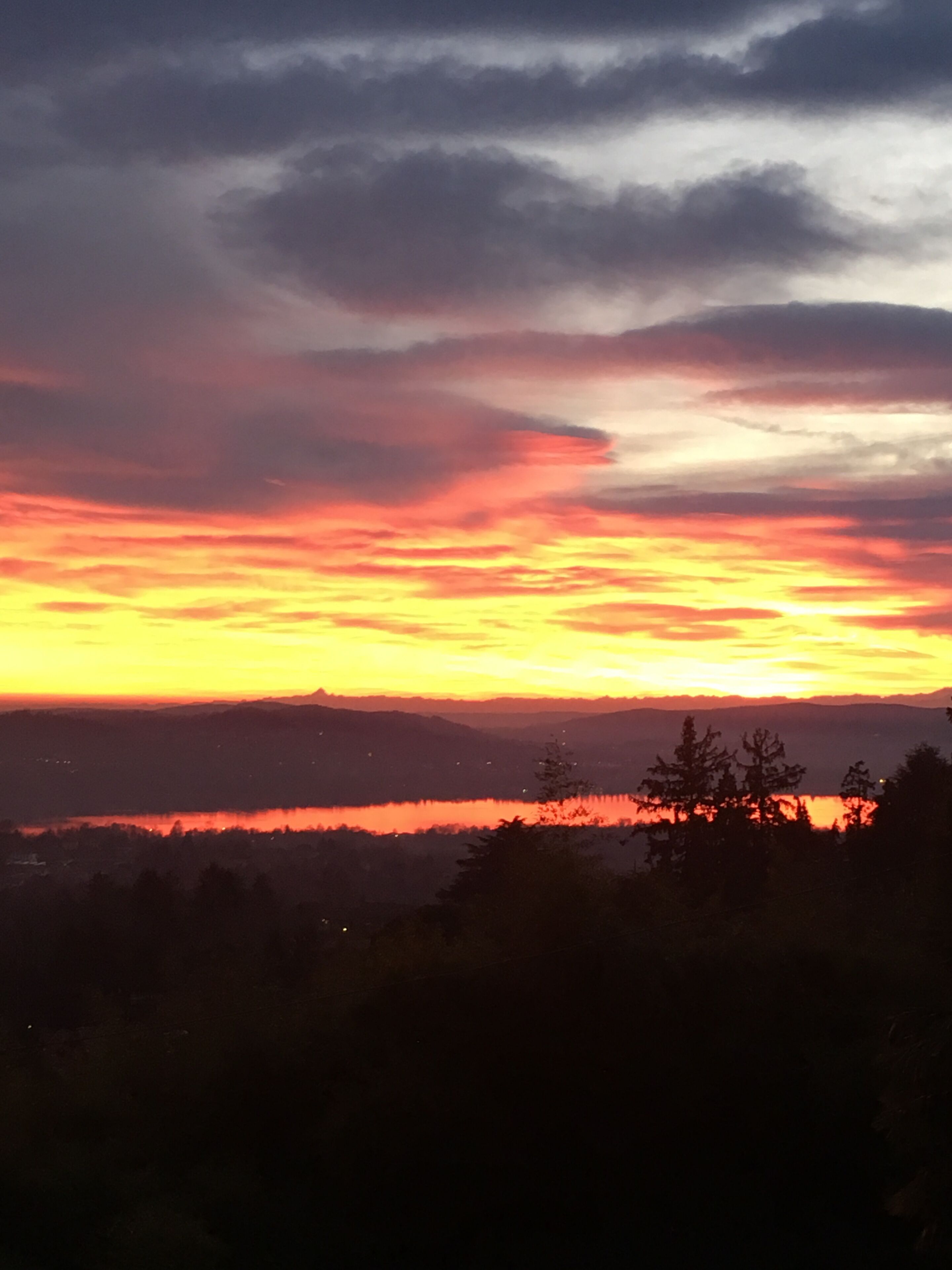 Ein Sonnenuntergang über einer Berglandschaft mit einem See im Vordergrund.