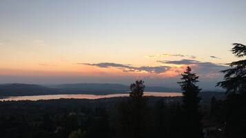 Vista panorámica de un lago rodeado de colinas y árboles al atardecer.