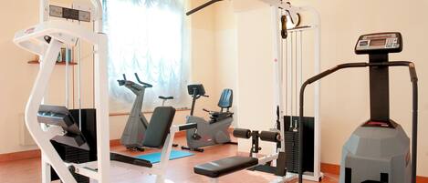 A home gym with various exercise equipment including a treadmill, stationary bike, and weight machines.