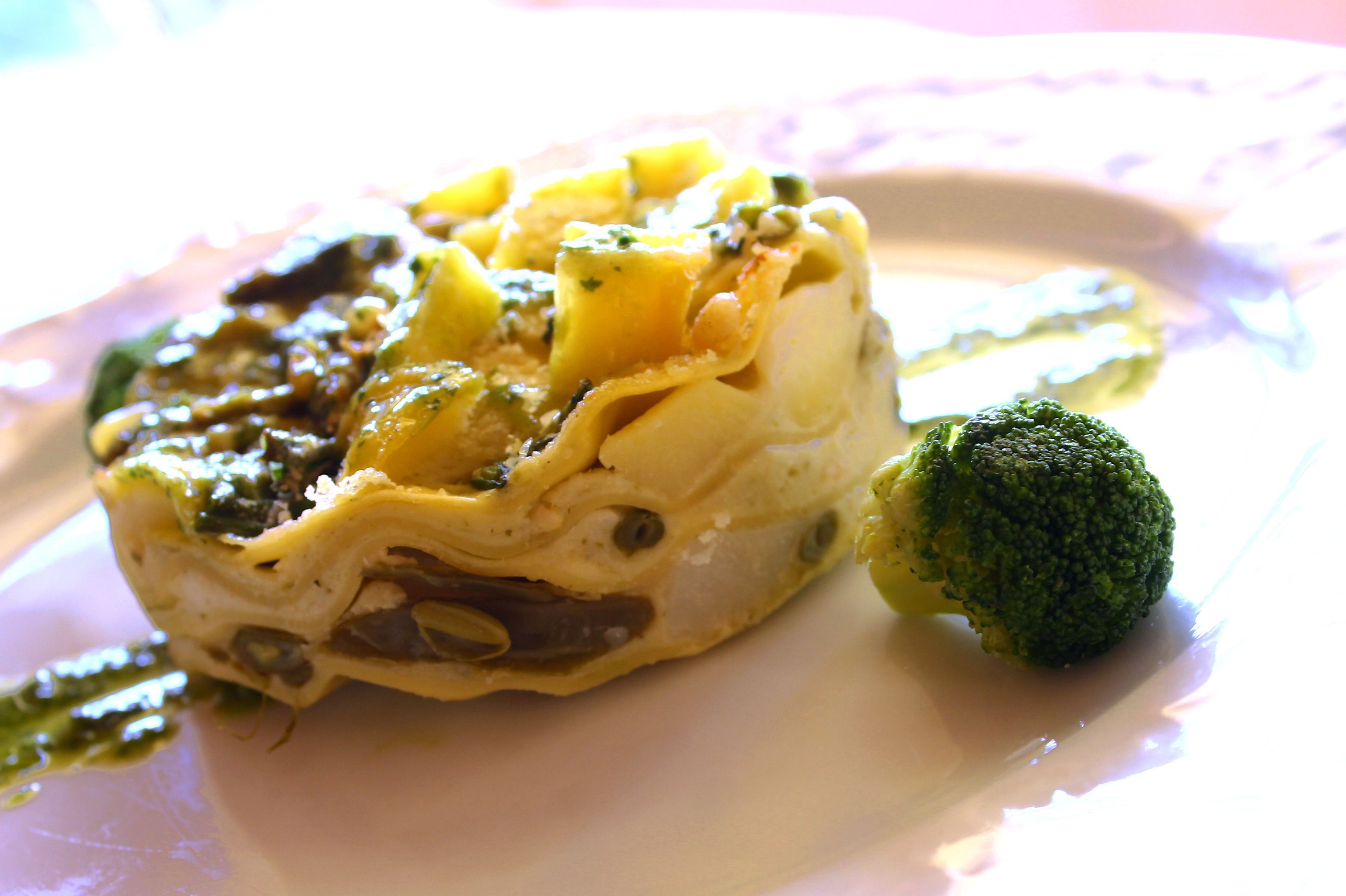 A plate with a rolled pastry, broccoli, and sauce.