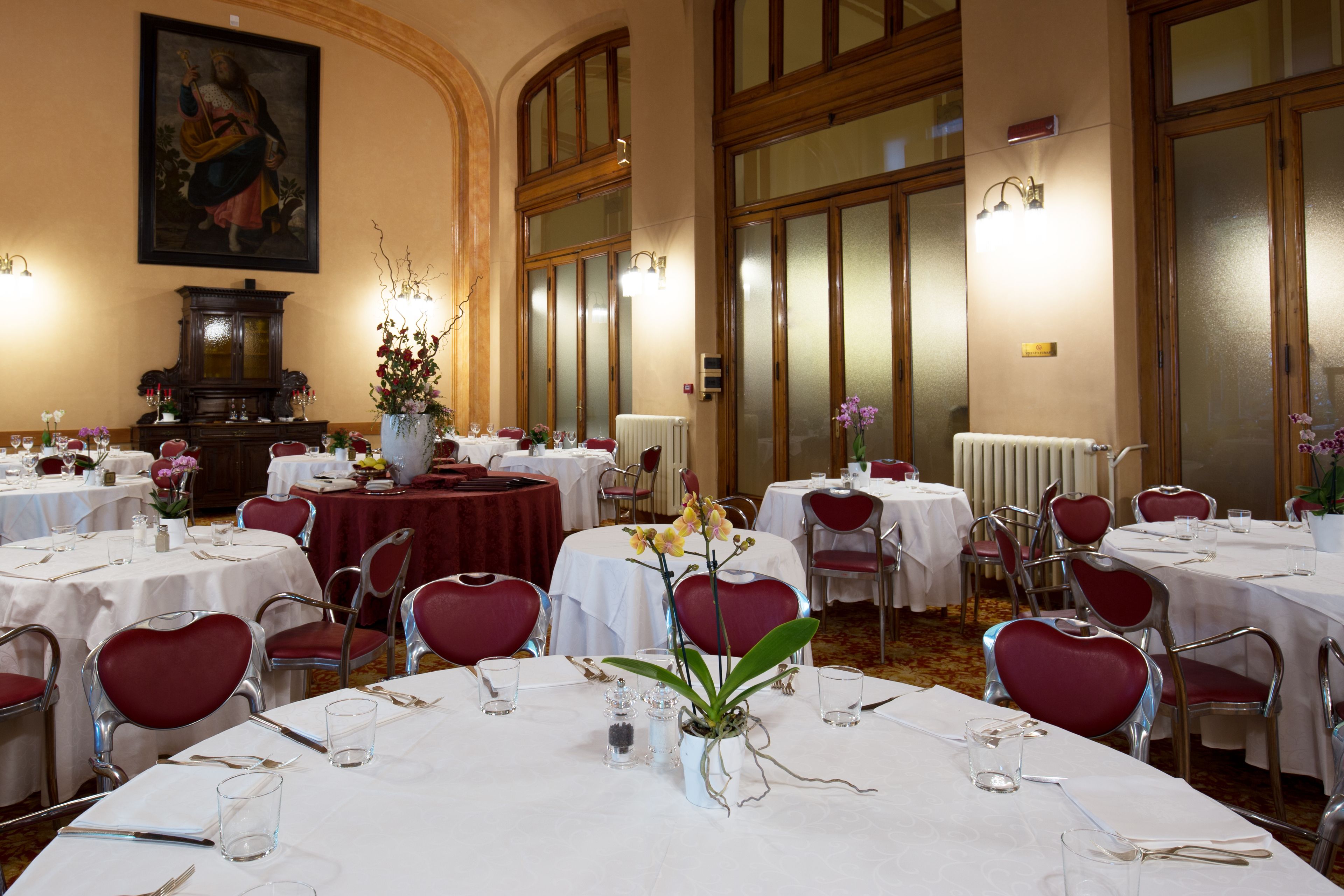 Une salle à manger élégante, avec des tables rondes, des chaises rouges en forme de cœur et des nappes blanches.
