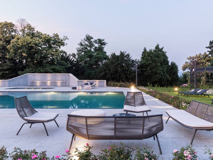 A poolside area with a modern outdoor seating arrangement, a fire pit, and a pergola structure.