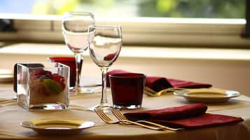Una mesa dispuesta para comer, con vasos transparentes, una servilleta roja y una copa de bebida roja.