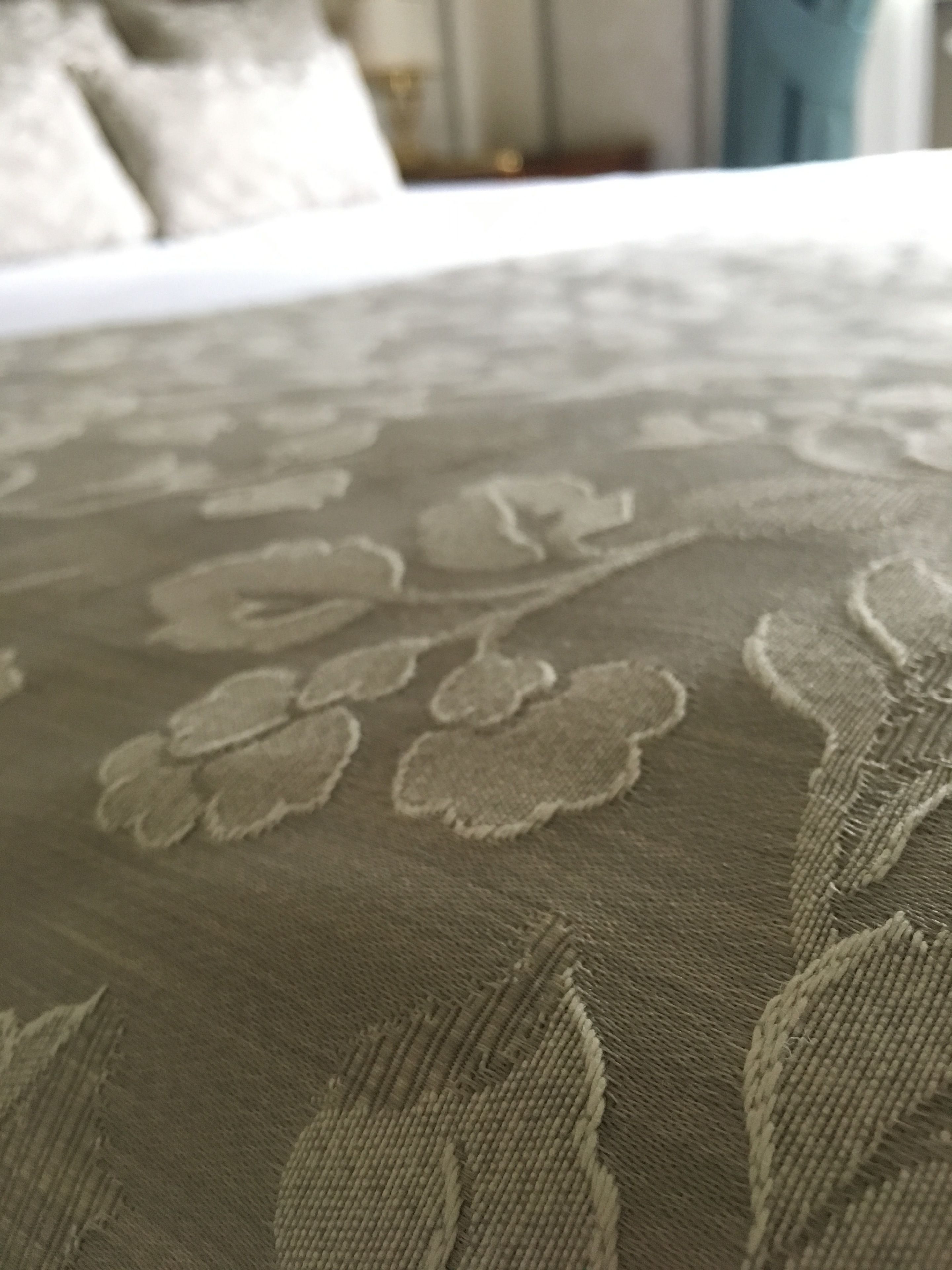 A close-up of a textured fabric with a floral pattern, likely part of a bedspread or upholstery.