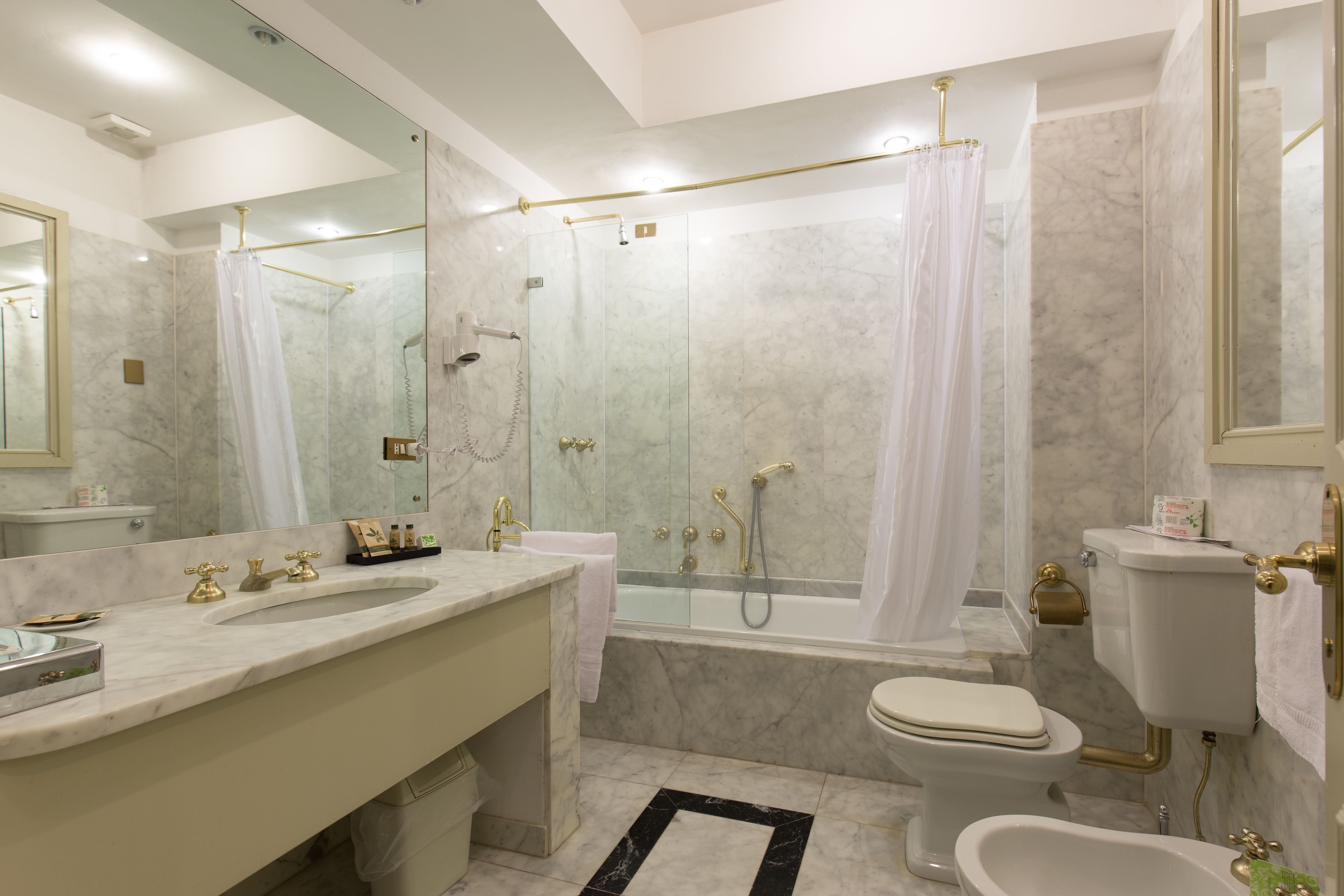 A modern bathroom with a marble sink, a bathtub, and a toilet.