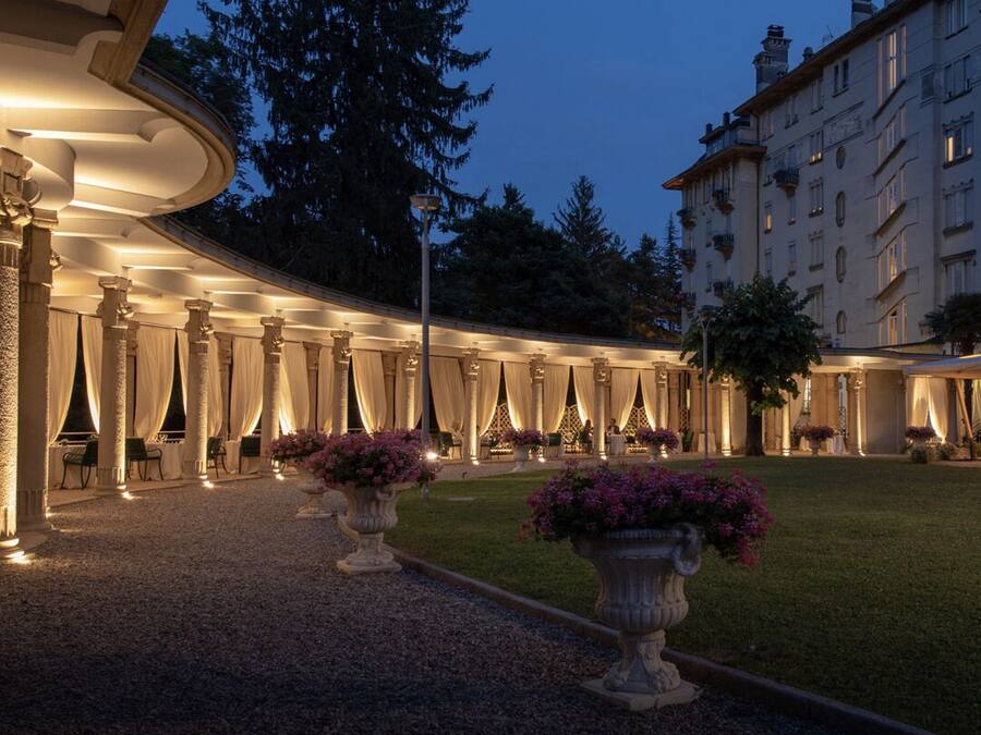 A historic hotel courtyard with columns, outdoor seating, and a well-lit entrance.